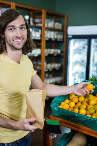 Homme sélectionnant des oranges dans la section organique — Photo