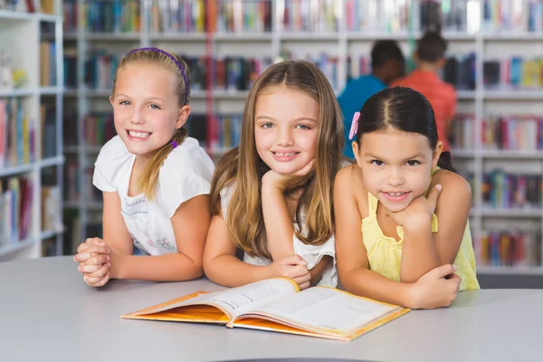 Dzieci w szkole razem czytając książkę w bibliotece — Zdjęcie stockowe