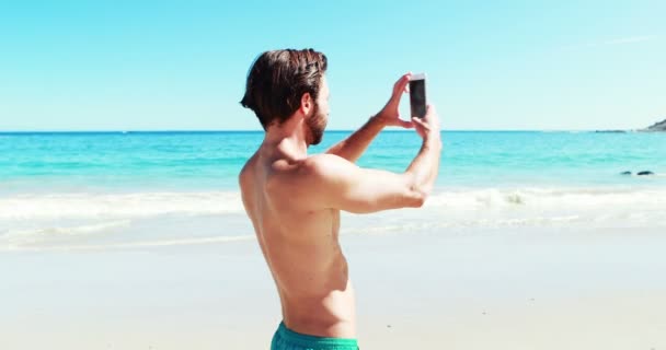 Junger Mann dreht Video am Strand — Stockvideo