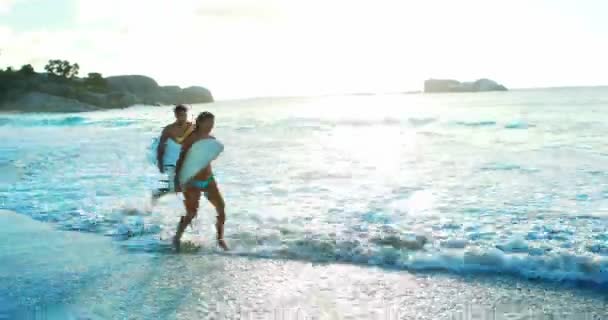 Pareja corriendo en la playa con tabla de surf — Vídeo de stock