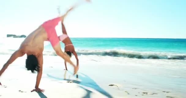 Casal realizando salto mortal na praia — Vídeo de Stock