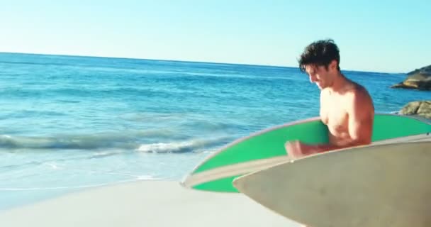 Pareja corriendo en la playa con tabla de surf — Vídeo de stock