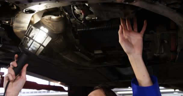 Female mechanic examining car with flashlight — Stock Video