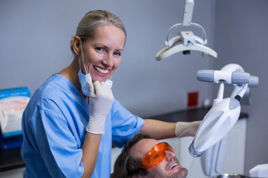 Dental assistant examining young patient mouth clipart