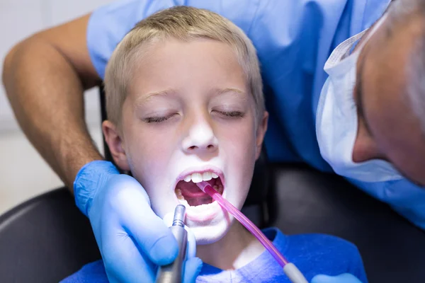 Dentista examinando a un paciente joven con herramientas —  Fotos de Stock
