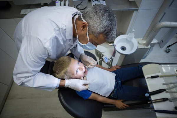 Стоматолог досліджує молодого пацієнта за допомогою інструментів — стокове фото