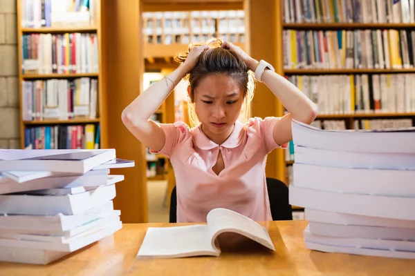 Jovem tensa estudando na biblioteca — Fotografia de Stock