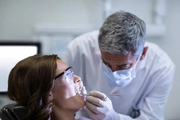 Стоматолог вивчає пацієнта-жінку з інструментами — стокове фото