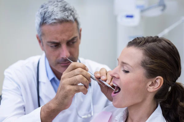 Dentista examinando a una mujer con herramientas — Foto de Stock