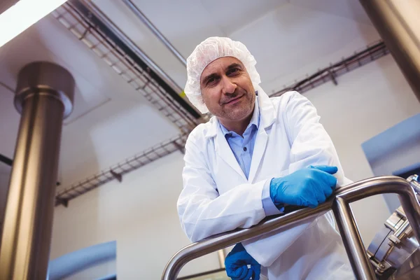 Smiling manufacturer leaning on pipe at brewery — Stock Photo, Image