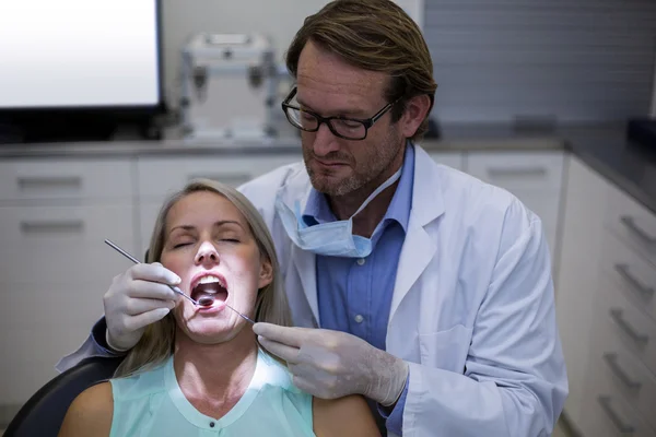 Dentista examinando uma mulher com ferramentas — Fotografia de Stock