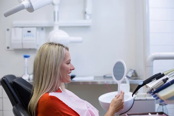 Patiënt controleren haar tanden in spiegel — Stockfoto