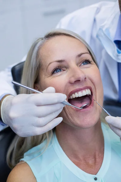 Dentista examinando uma mulher com ferramentas — Fotografia de Stock