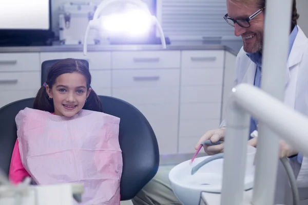 Sonriente paciente joven sentado en la silla de dentistas — Foto de Stock