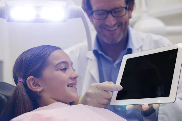 Дантист показывает молодому пациенту цифровой планшет — стоковое фото