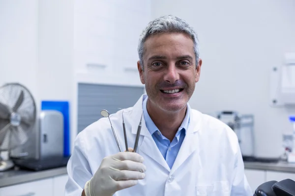 Portrait of smiling dentist holding dental tools — Stock Photo, Image