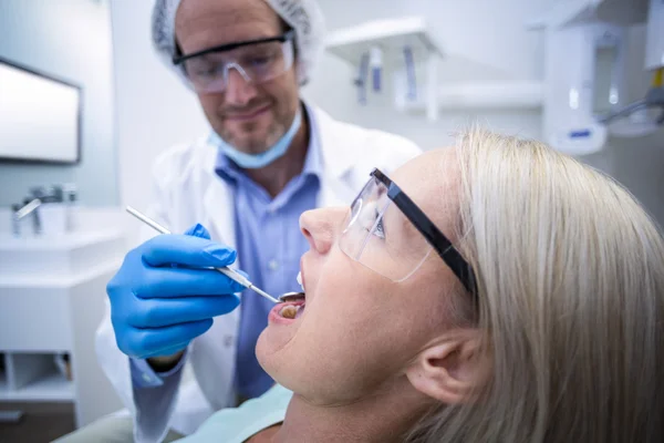 Dentista examinando uma mulher com ferramentas — Fotografia de Stock