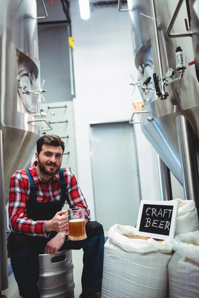 Manufacturer with beer glass while sitting at brewery — Stock Photo, Image