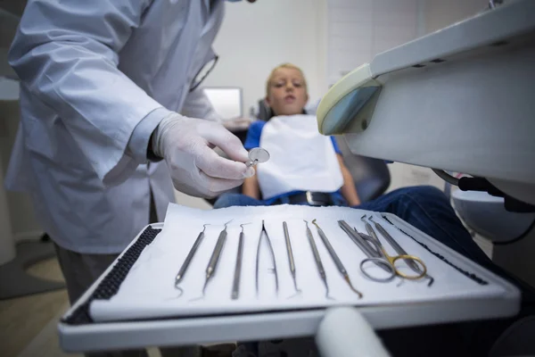 Οδοντίατρος μαζεύοντας Οδοντιατρικά εργαλεία για να εξετάσει ένα νεαρό ασθενή — Φωτογραφία Αρχείου