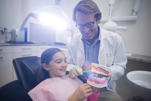 Dentist showing young patient how to brush teeth — Stock Photo, Image