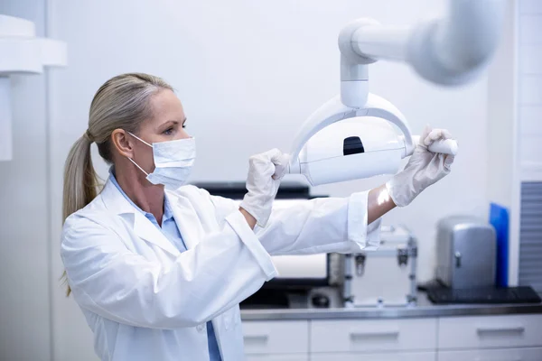 Female dentist adjusting dental lights — Stock Photo, Image