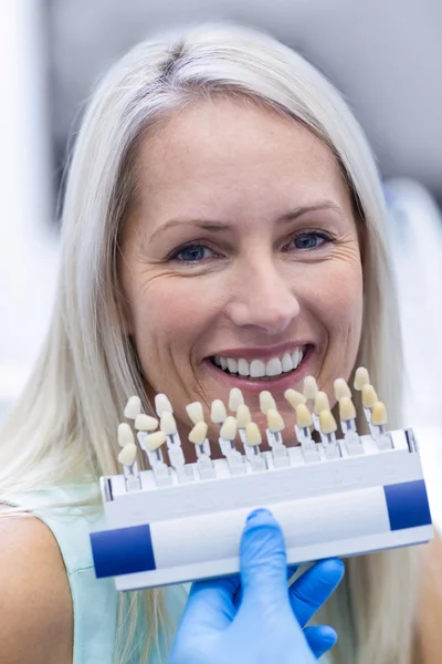 Dentista segurando tons de dentes enquanto o paciente do sexo feminino sorrindo — Fotografia de Stock