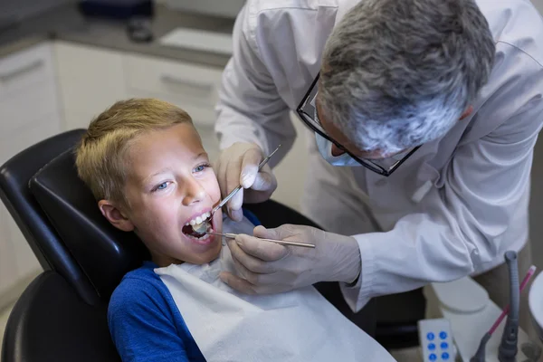 Dentista examinando um paciente jovem com ferramentas — Fotografia de Stock