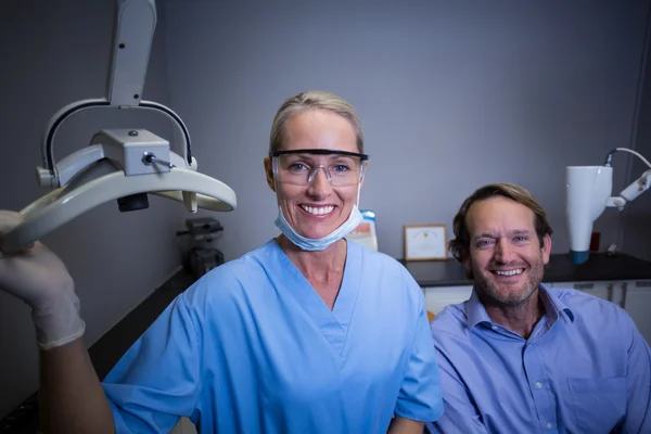 Usmívající se zubní asistent nastavení světla v klinice — Stock fotografie