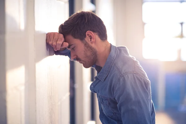 Empresário cansado inclinado na parede — Fotografia de Stock