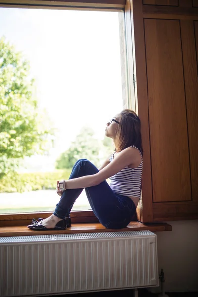 Doordachte vrouw zitten op de vensterbank — Stockfoto