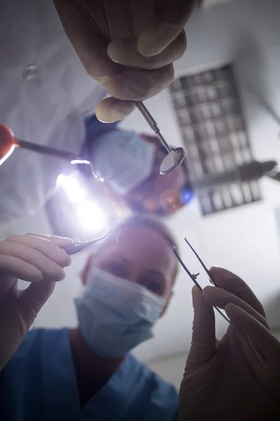 Dentista em máscara cirúrgica segurando ferramentas dentárias — Fotografia de Stock