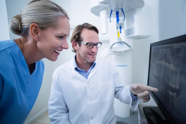 Dentista e assistente dentário discutindo um raio-x no monitor — Fotografia de Stock