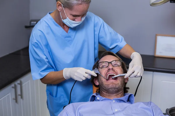 Dentista examinando um paciente jovem com ferramentas — Fotografia de Stock