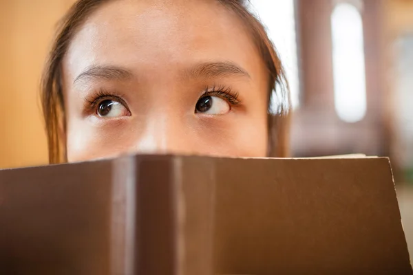 Jovem mulher atenciosa cobrir seu rosto com livro — Fotografia de Stock