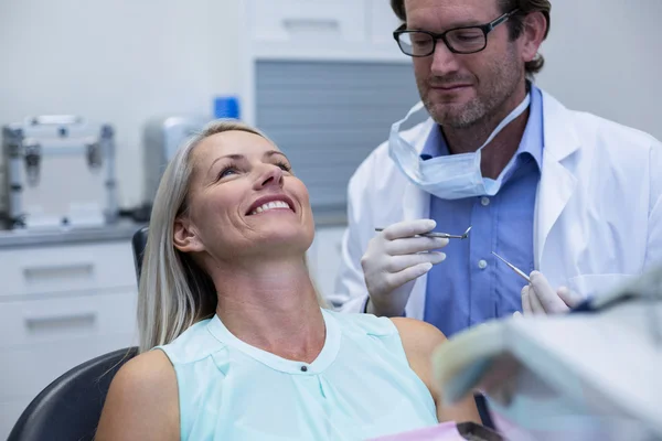 Dentista che esamina una donna con gli strumenti — Foto Stock