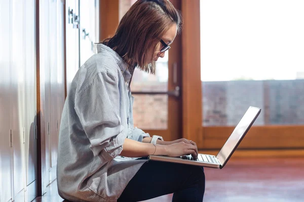 Jovem mulher usando laptop no vestiário — Fotografia de Stock