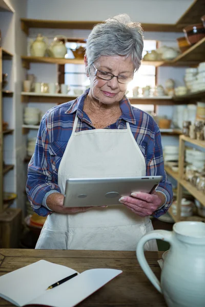Attentive female potter using tablet — Stock Photo, Image