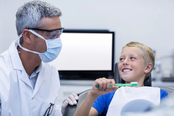 Dentiste assister le jeune patient tout en brossant les dents — Photo