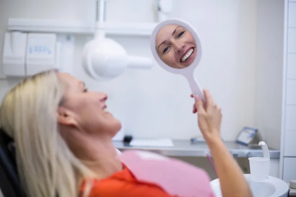 Пациентка проверяет зубы в зеркале — стоковое фото