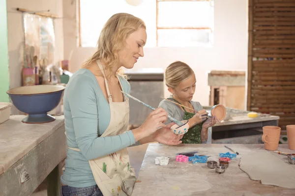 Potter and girl painting in pottery workshop — Stock Photo, Image