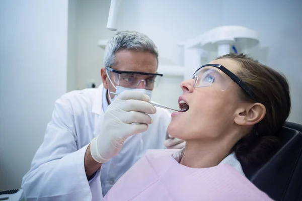 Dentista che esamina una donna con gli strumenti — Foto Stock