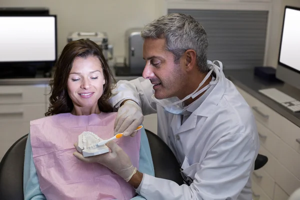 Dentista mostrando modelo de boca para paciente do sexo feminino — Fotografia de Stock