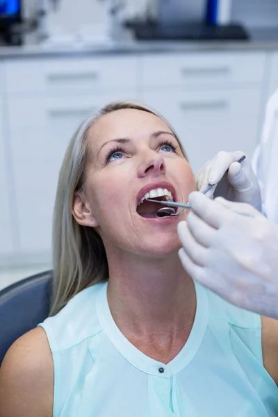 Dentista examinando a una mujer con herramientas — Foto de Stock