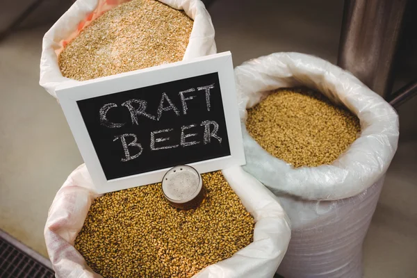 Teken boord met verschillende gerst in zak in brouwerij — Stockfoto