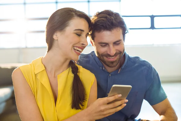 Female business executive showing mobile phone to co-worker — Stock Photo, Image