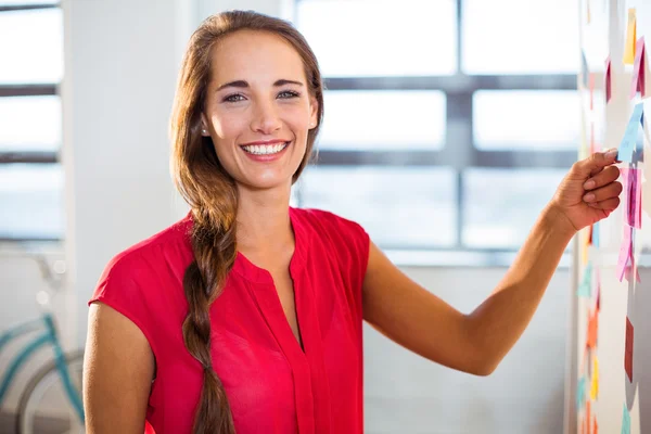 Woman putting sticky notes on whiteboard