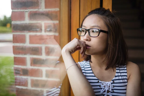 Thoughtful woman sitting on windowsill — Stock Photo, Image