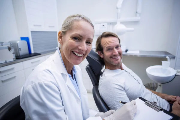 女性歯科医の男性を操作しながらのクリップボードに書き込み — ストック写真