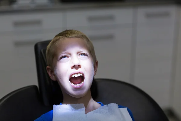 Młody pacjent siedzi na fotelu u dentysty z otwartymi ustami — Zdjęcie stockowe