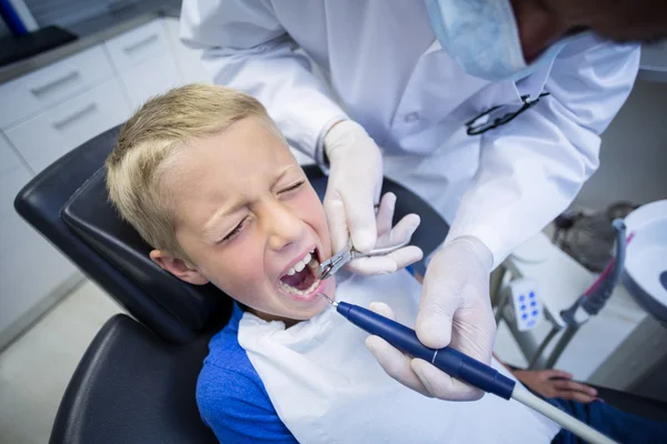 Dentiste examinant un jeune patient avec des outils — Photo